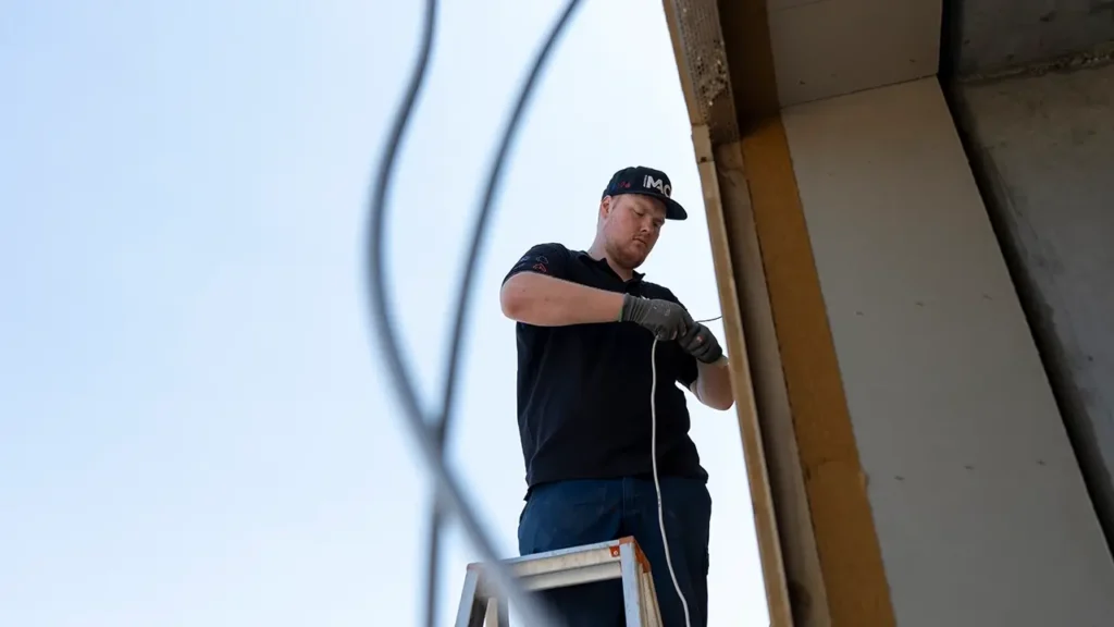 Mitarbeiter von Mack Haustechnik bei Elektroinstallation auf Baustelle – Handwerker bei der Arbeit auf Leiter